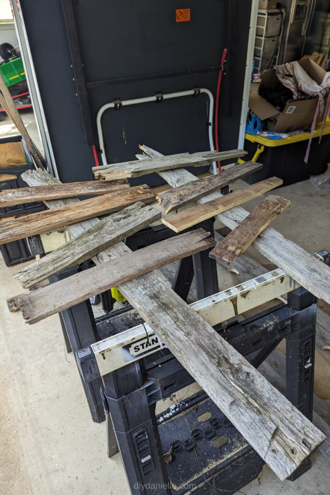 Pallet wood pieces that are short and broken, laid haphazardly on top of a wood 'post' made from pallet wood. These are to form a spooky sign.