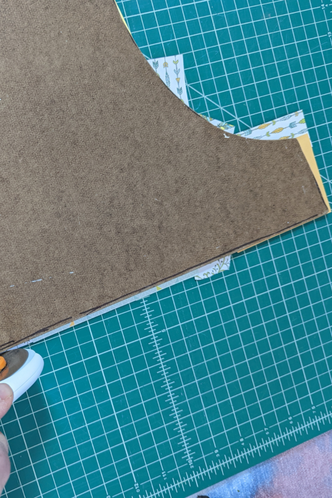 Pattern form that has been turned into artwork using scrapbook paper. Photo shows step of cutting the excess paper away from the back. 