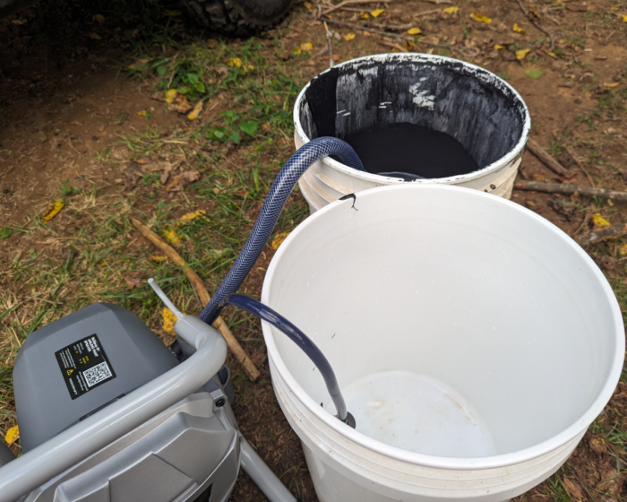 Two buckets set up to prime the airless paint sprayer before painting.