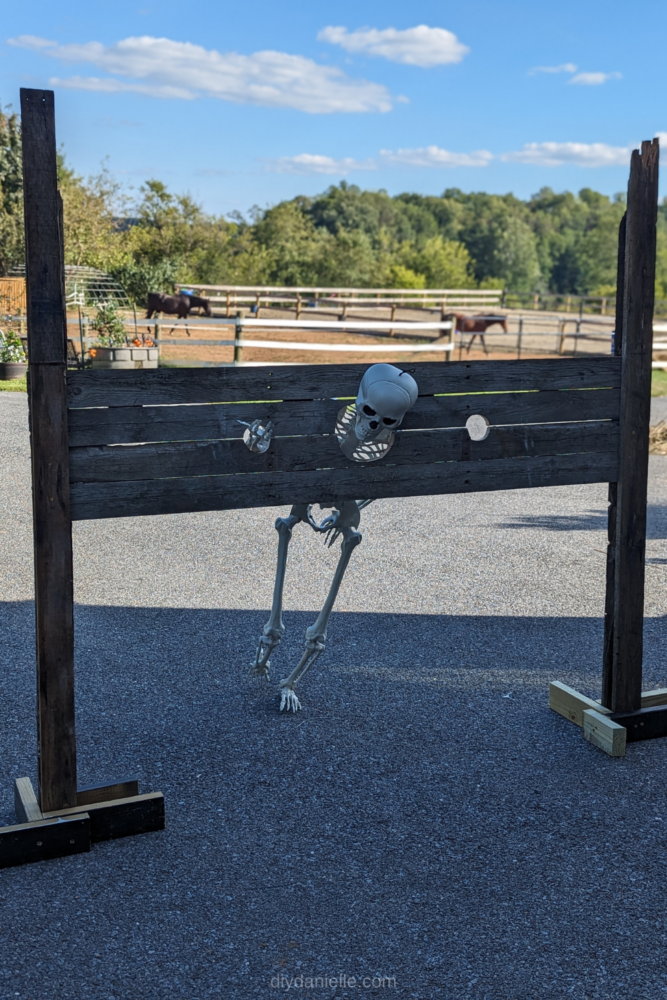How to make medieval stocks for Halloween decorations using old pallets. This is such a fun and easy project! Skeleton in the stocks with one hand out (he wasn't flexible enough for the spacing I used). Horse farm blurred out in the background.
