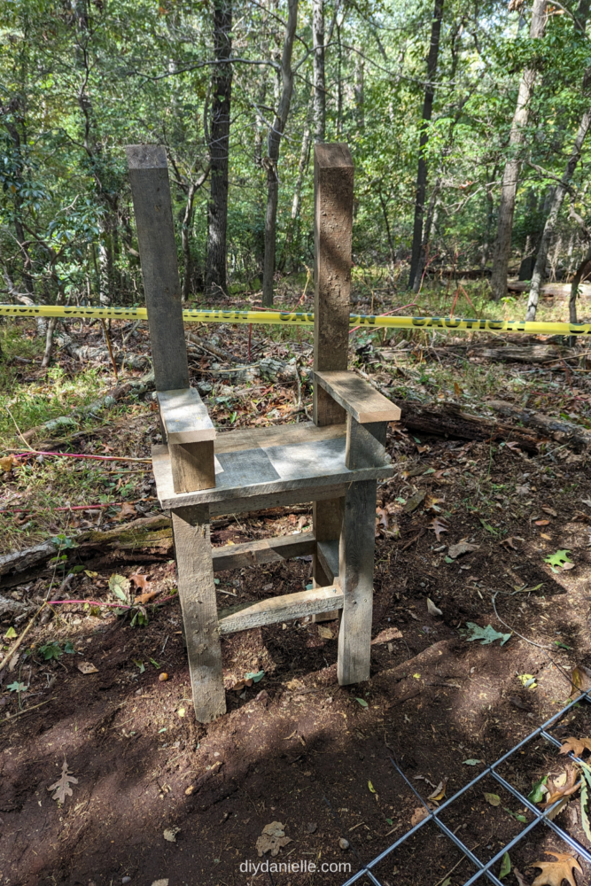 How to make a DIY electric chair prop. This outdoor Halloween decoration is made out of lots of aged scrap wood! 

Image: Photo of a fake electric chair setup in the woods with caution tape behind it.  The head piece, back of the chair, and straps haven't been added yet. 

The wood is all old and looks aged.