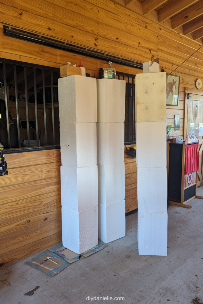Four foam blocks per column and three columns, side by side and weighted down while the spray foam adhesive dries in a barn aisle. 