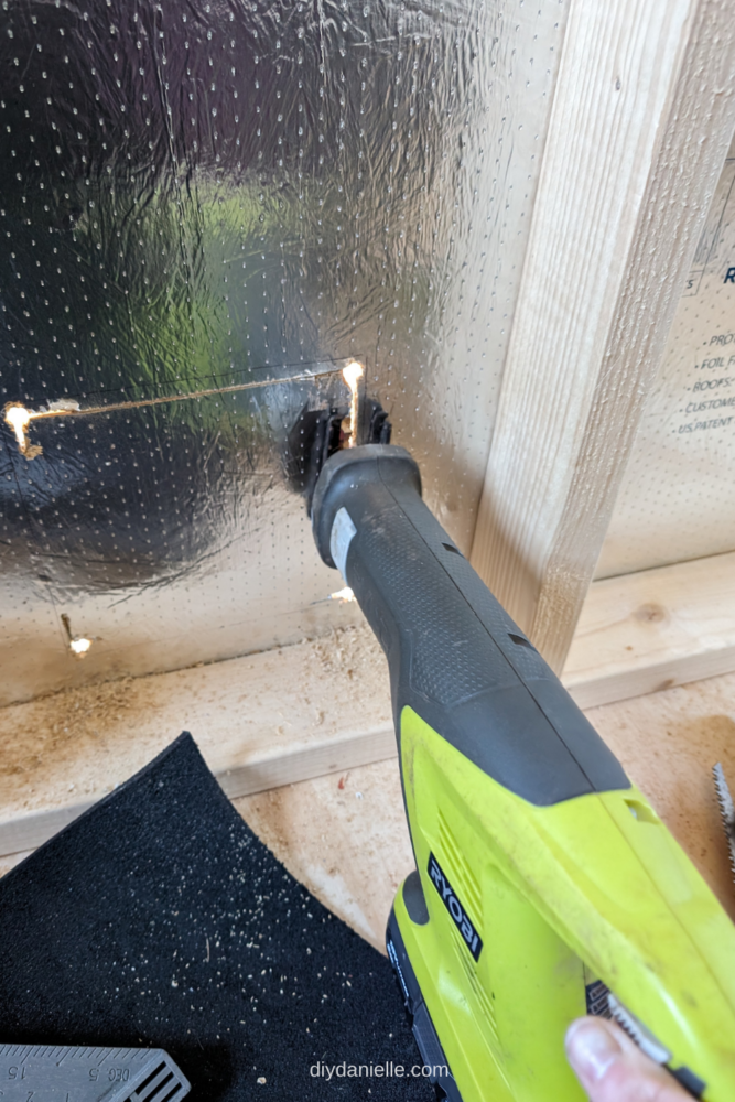 A reciprocating saw cutting a square for the cat door through the shed’s interior insulation.