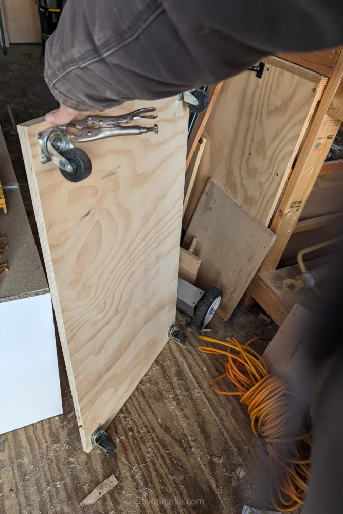 Four casters are attached to the wooden base to help the DIY microwave cart roll.
