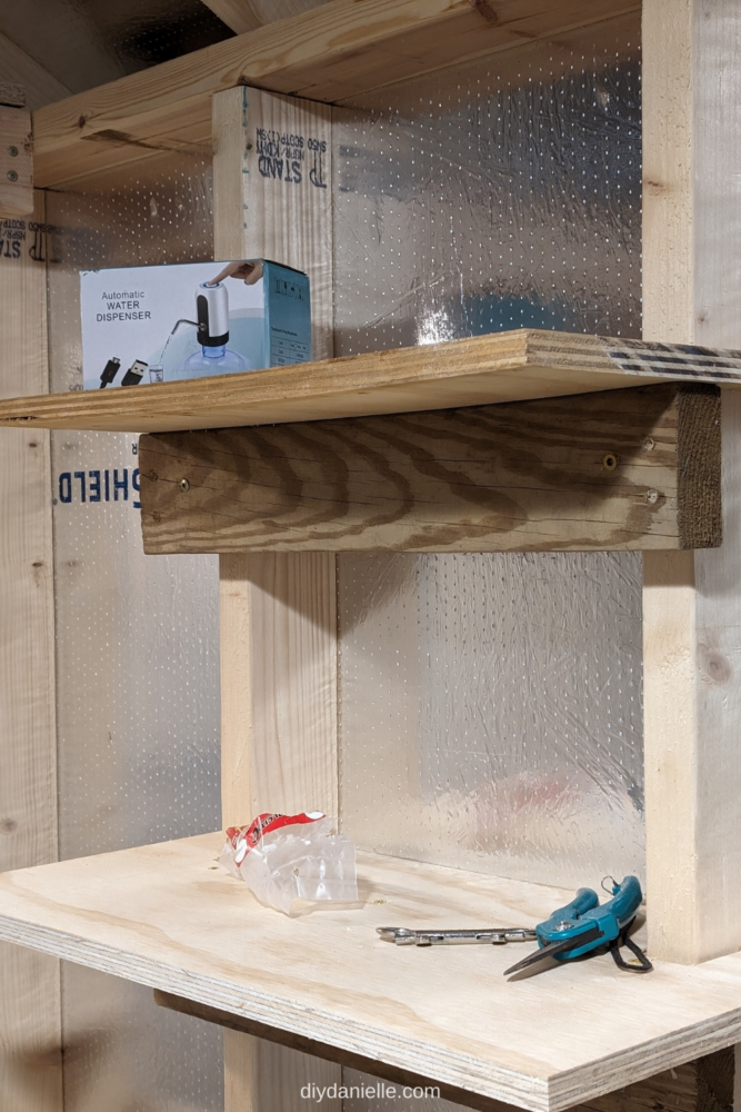 How to Make Between the Studs Shelves: Photo of 2 basic 3/4" plywood shelve attached to studs inside a small shed. The shelves are holding some trash and tools from the DIY project.