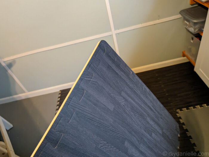 Foam floor tile in dark gray wood grain with the trim pieces on it.