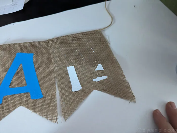 Iron on vinyl that has been partially peeled off of burlap banner.