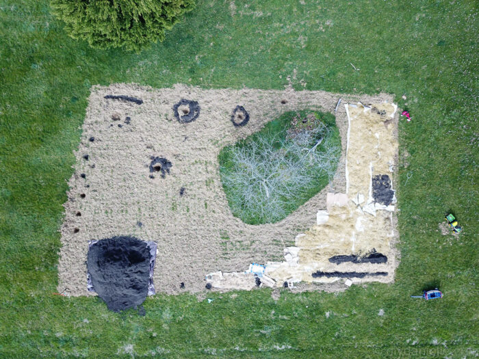 Drone view of initial food forest setup showing cardboard weed barrier and compost layering in garden space.