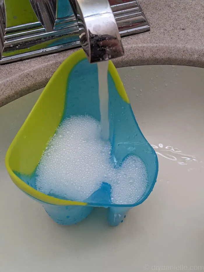 a continuous flow of water and a blue container under with shampoo. catching the waters and forming bubles