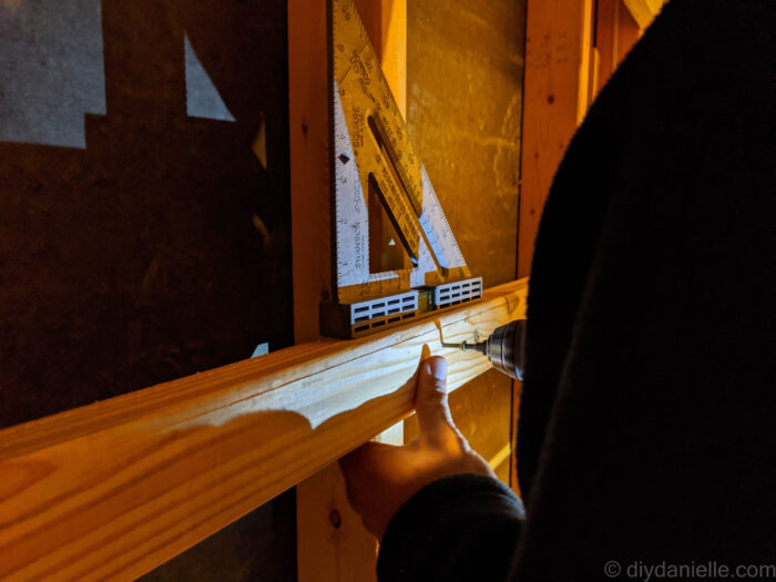 Screwing in a support for a basement storage shelf and ensuring that it's level.