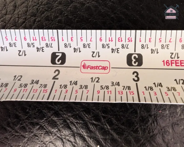 a detailed close up visual representation of the tape measure. it includes both feet and inches measurement.

There are markings for 1/8 inches and 1/4 inches. The colors for the 1/16 marks are in pink.