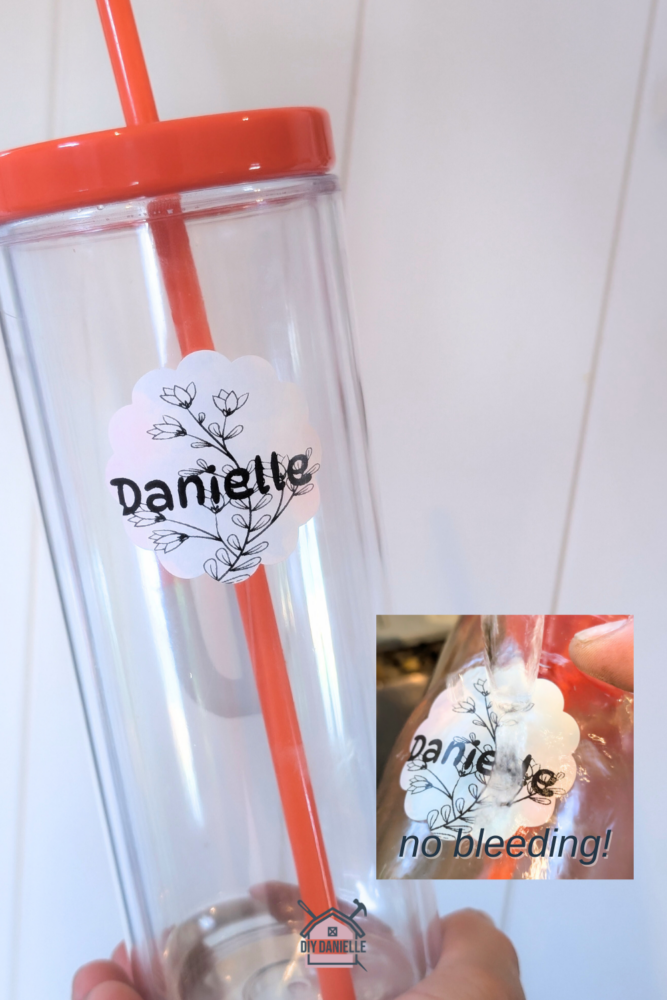 Waterproof sticker that has a flower outline and the name DANIELLE on it. This label is on a clear water bottle with an orange lid. In a smaller box inside the photo is a small box with the label being rinsed under water. The 'ink' isn't running because it's an ink-free printer. The text in the box says "no bleeding!"