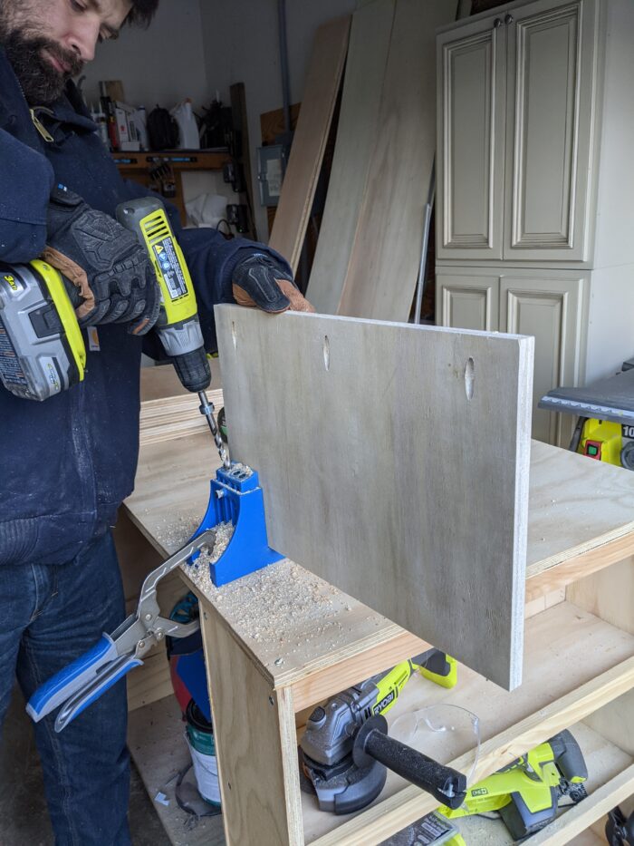 Before assembling the pieces, drill all necessary pocket holes in your wood to prepare for easy assembly. Photo of a man using a Ryobi drills to add pocket holes to the shelves of the DIY cabinet.