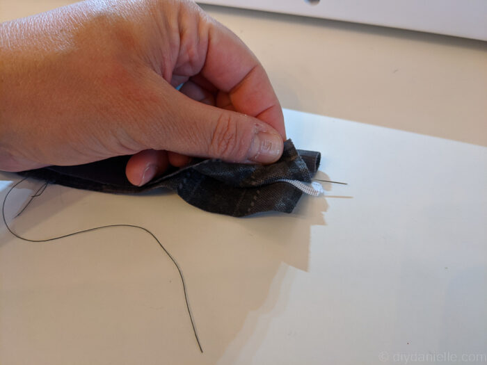 Close-up of folded fabric with a small elastic loop tucked inside, showing raw edges ready for sewing.