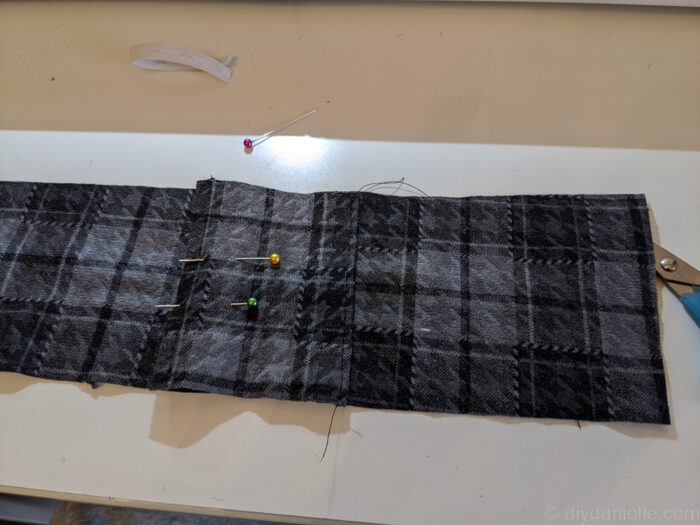 Close-up of a fabric pocket sewn at the bottom and pinned at the top onto a guitar strap.