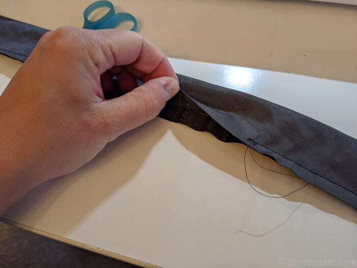 Close-up of a partially sewn fabric guitar strap with a small opening left on the long side for turning.
