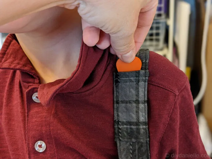 Close-up of a fabric guitar strap with a small pocket holding a guitar pick.