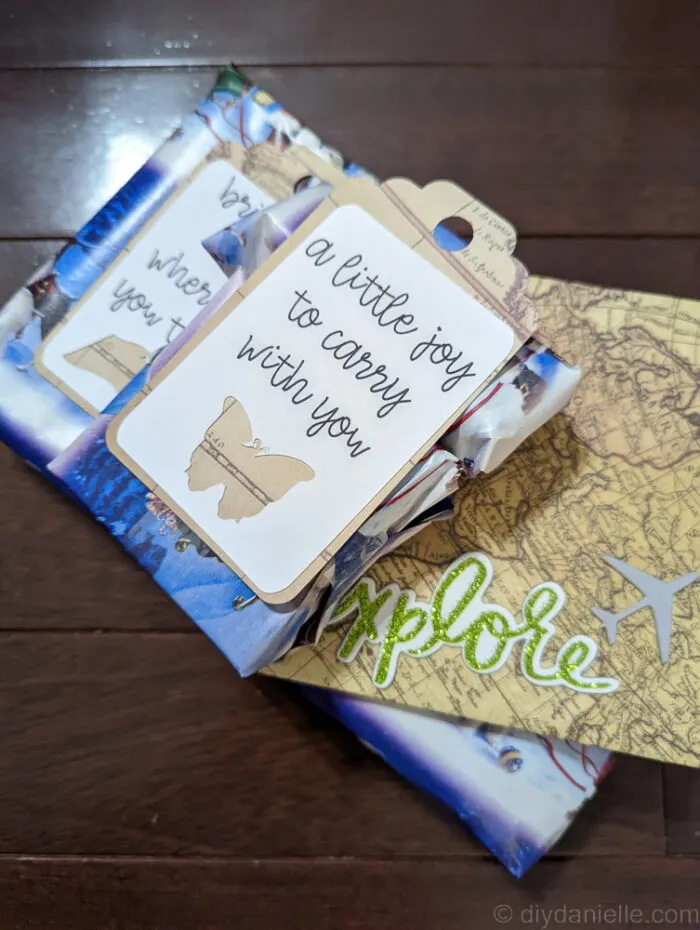 Small gifts wrapped in wrapping paper and cardstock, with a tag made with the Cricut Maker 3, Cardstock, and Smart Sticker paper. The tags say "explore" with an airplane" "a little joy to carry with you."