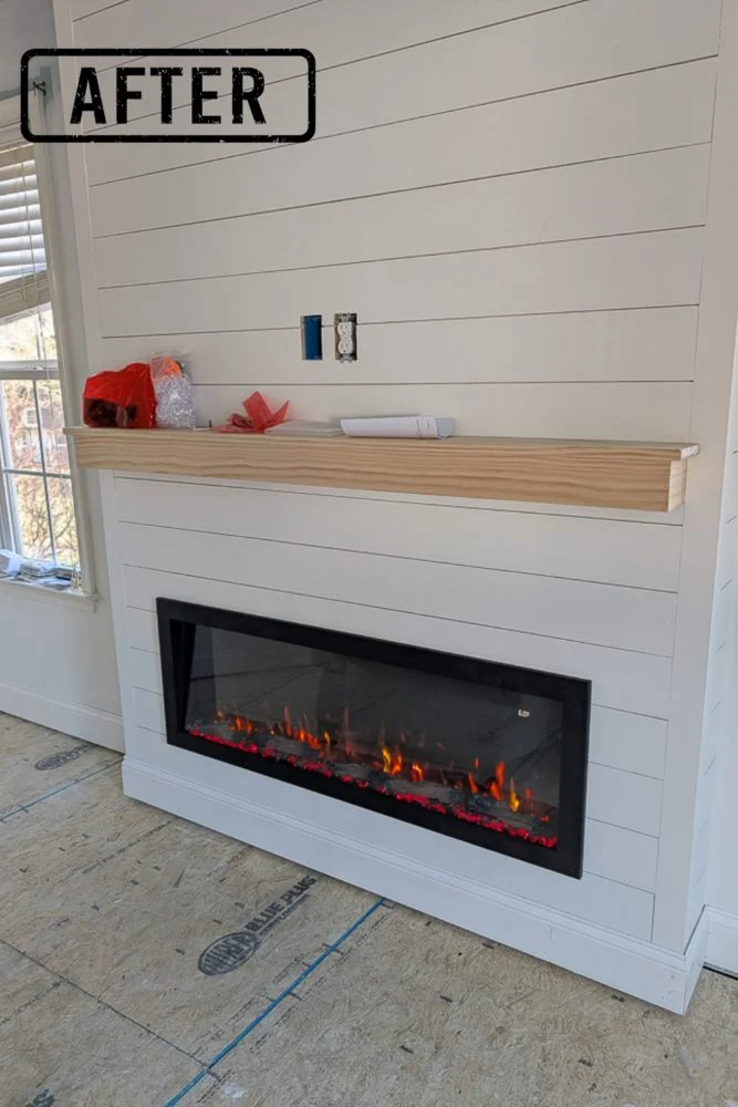After photo of our wood burning fireplace after converting it to an electric fireplace. There's a bump out, white shiplap and a small mantle made of raw wood. We will eventually hang a tv over the mantle and you can see the outlets there.