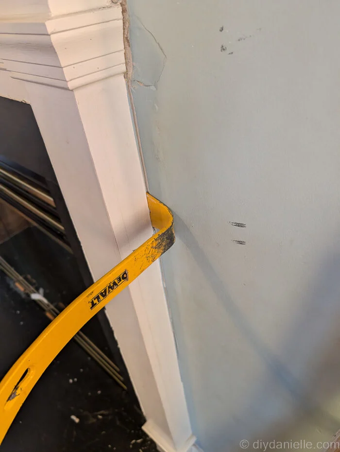 Using a pry bar to remove the original mantle for the wood burning fireplace.