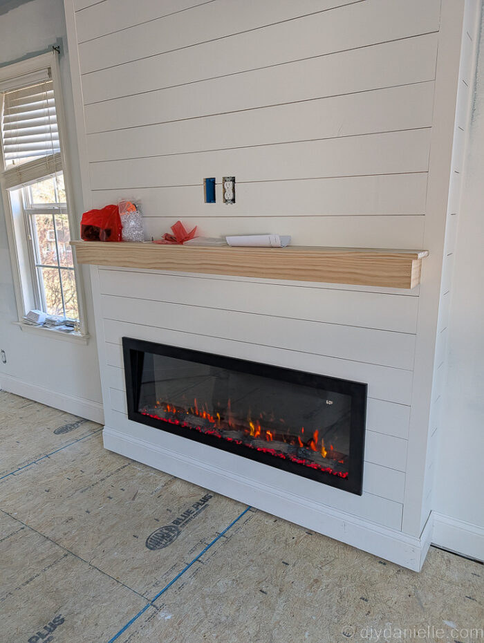 Before-and-after view showing the old wood-burning fireplace replaced with a modern electric fireplace.