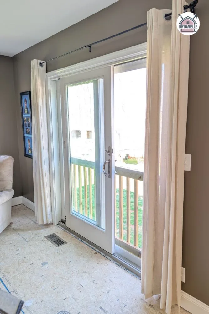 We replaced two large windows in a living room that were side by side with a sliding glass door. Linen curtains in natural colored fabric. Anderson Sliding Glass Door. Paint color is Behr Native Soil.