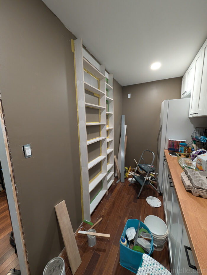 Shelves with 1x4 top and 1x6 bottom trim boards installed, edges cut at angles using a miter saw for a built-in appearance.

