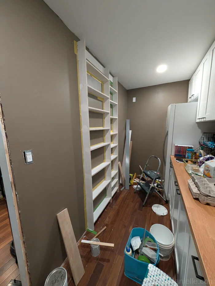 Shelves with 1x4 top and 1x6 bottom trim boards installed, edges cut at angles using a miter saw for a built-in appearance.


