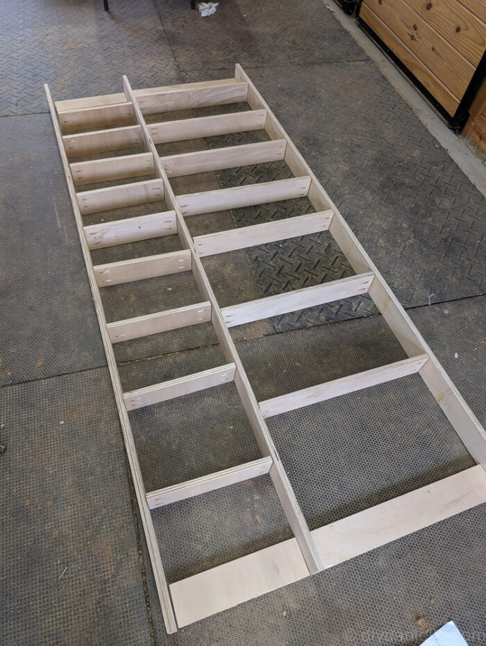 Unassembled shelves laid out in their planned positions, with flat wall-mounting pieces visible nearby.