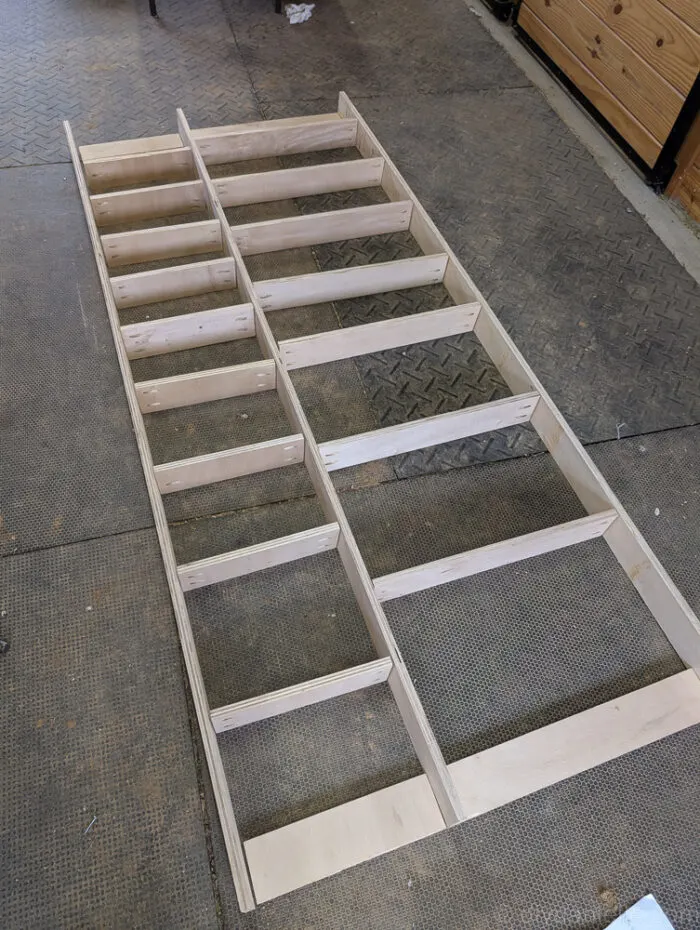 Unassembled shelves laid out in their planned positions, with flat wall-mounting pieces visible nearby.