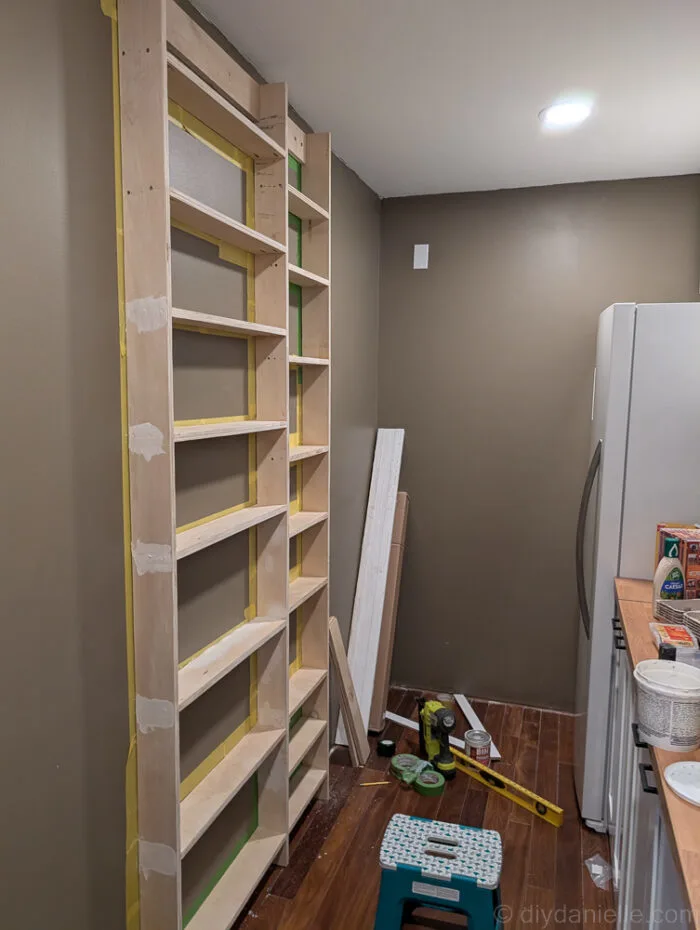 Shelving primed and walls taped off in preparation for adding pre-primed trim boards.