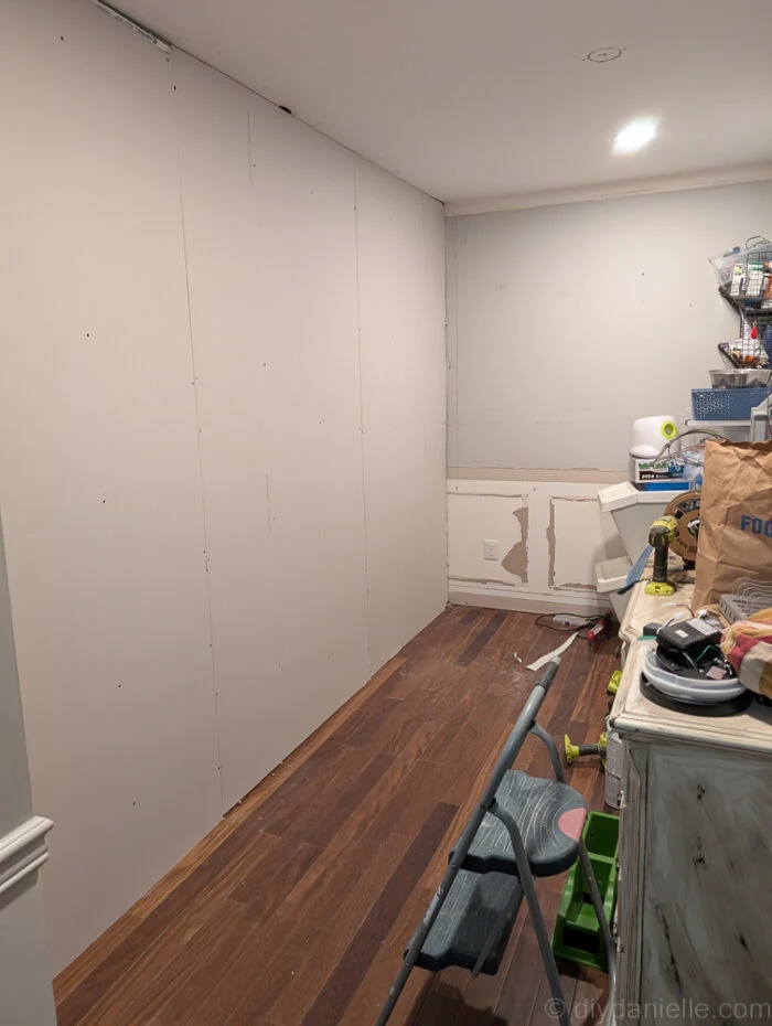 Drywall attached to the wall after the electrician finished installing outlets. Hallway side.