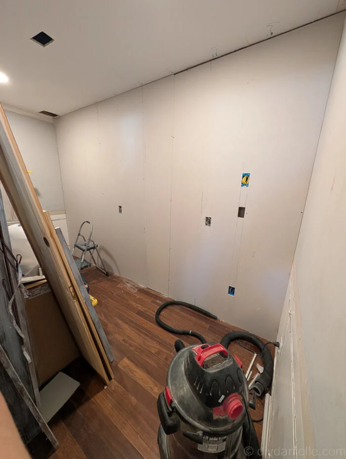 Drywall attached to the wall after the electrician finished installing outlets. Pantry side.