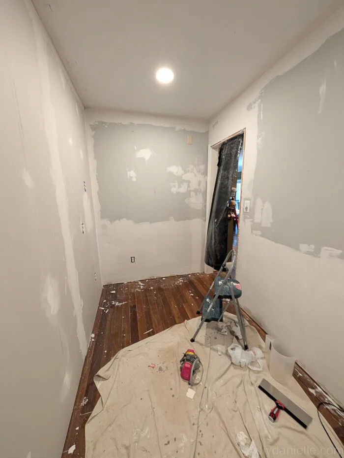 Below is a picture of that wall mid mudding (right side, as well as straight ahead)... if you compare to the new drywall we installed, we spent a LOT more time repairing this wall than the newer drywall panels (sigh). As you can see, we needed to cover nearly half the wall with drywall mud.