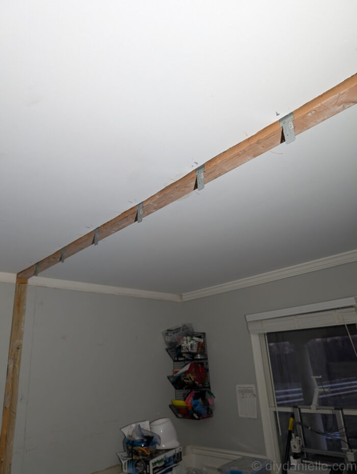 A long 2x4 was laid acrossed the ceiling where the cut out was, and attached to the framing above. You can see Simpson Strong Tie brackets placed and ready every 16" for the studs to be placed.