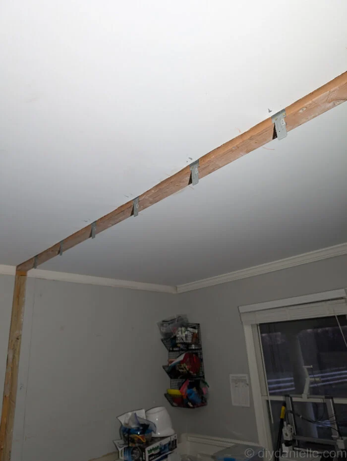 A long 2x4 was laid acrossed the ceiling where the cut out was, and attached to the framing above. You can see Simpson Strong Tie brackets placed and ready every 16" for the studs to be placed.