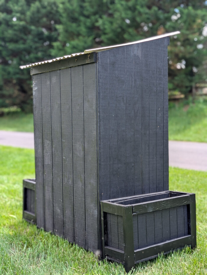Finished DIY farm stand positioned at the curb with roof and side planters attached, ready for use.


