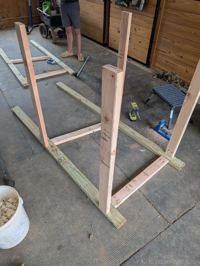 Partially built DIY wooden farm stand frame showing side panels connected with front trim pieces.