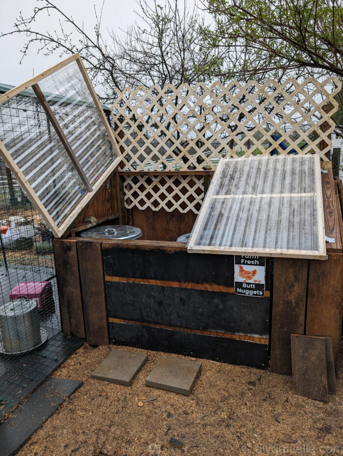 Hinged clear panel lids on a DIY feed shed designed to keep animal feed dry and protected.