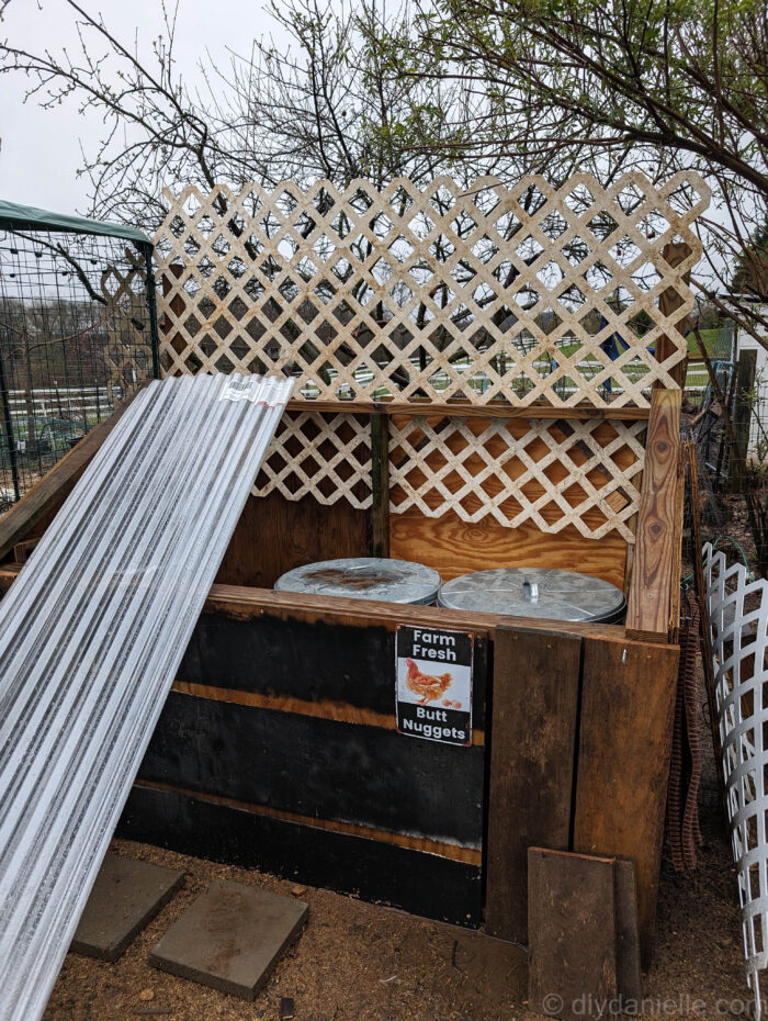 DIY feed shed with scrap wood siding and a trellis installed to block chickens from the garden.