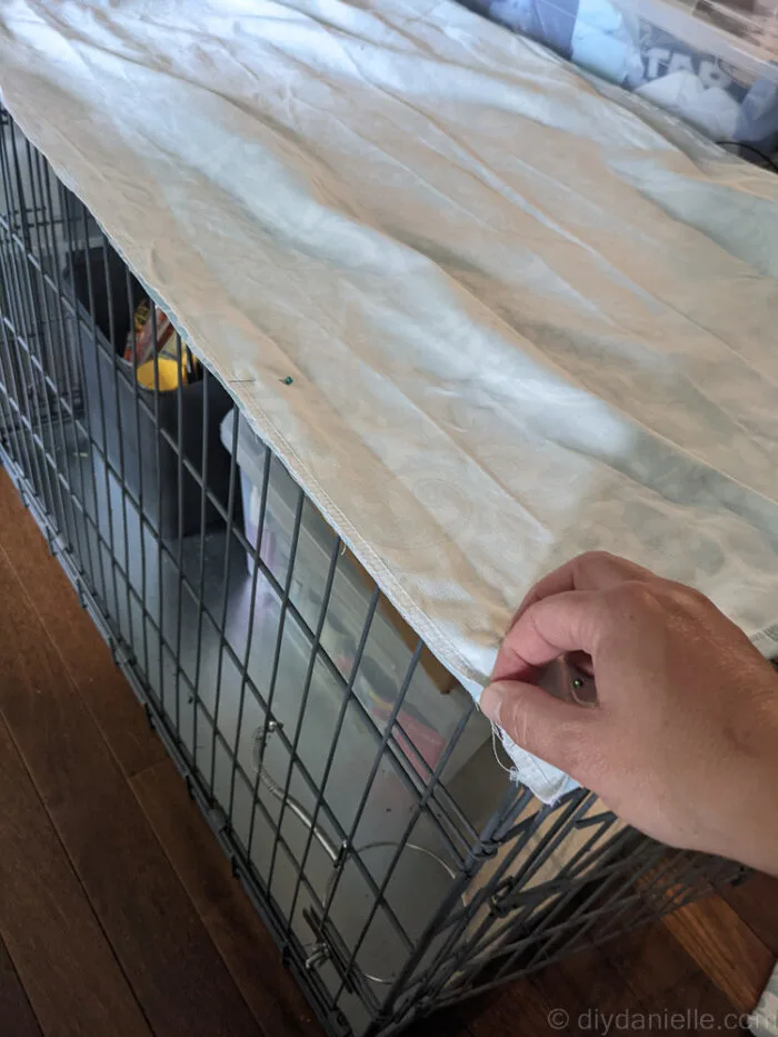 Hands sewing side panels to the top panel of a fabric dog crate cover, right sides together.