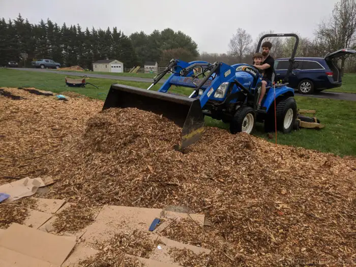 Close-up of heavy wood chip mulch pile with garden tools.