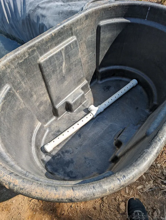 PVC pipe placed inside the bog filter trough with holes drilled for even water flow and capped ends.