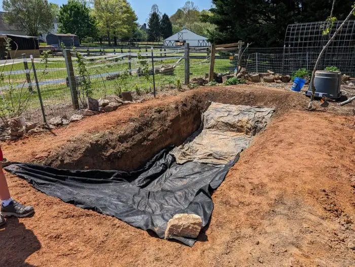 Laying underlayment in the pond to protect the liner, using budget-friendly materials for durability