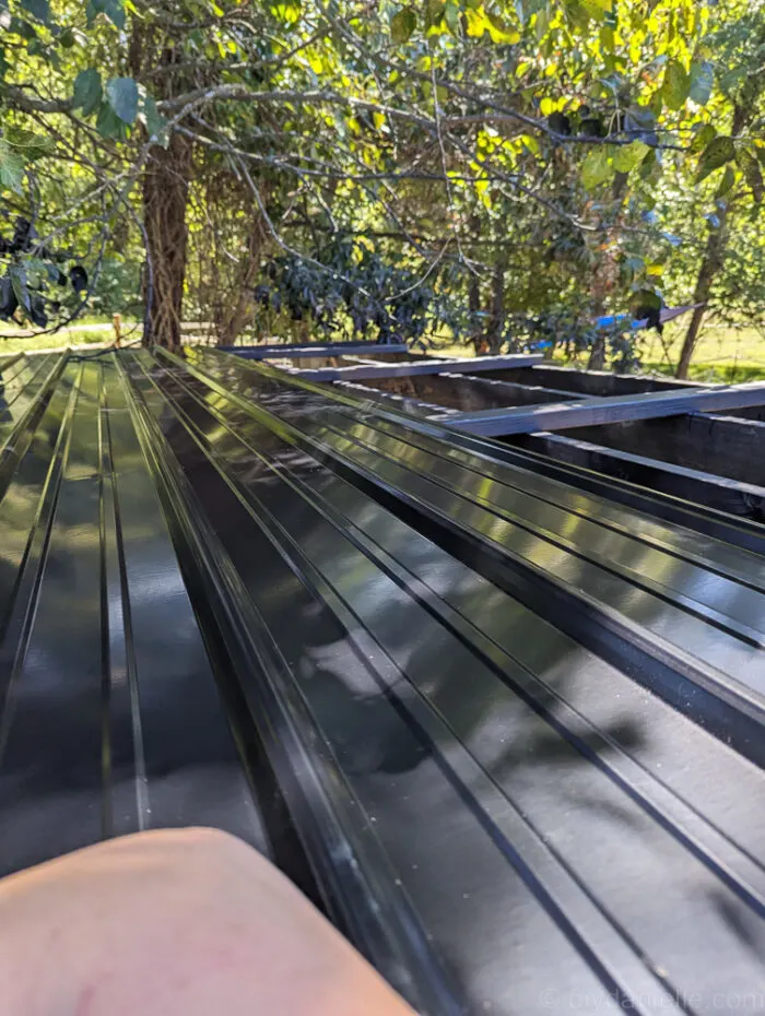 Metal roofing panels being installed on a wooden framed run-in shed roof.