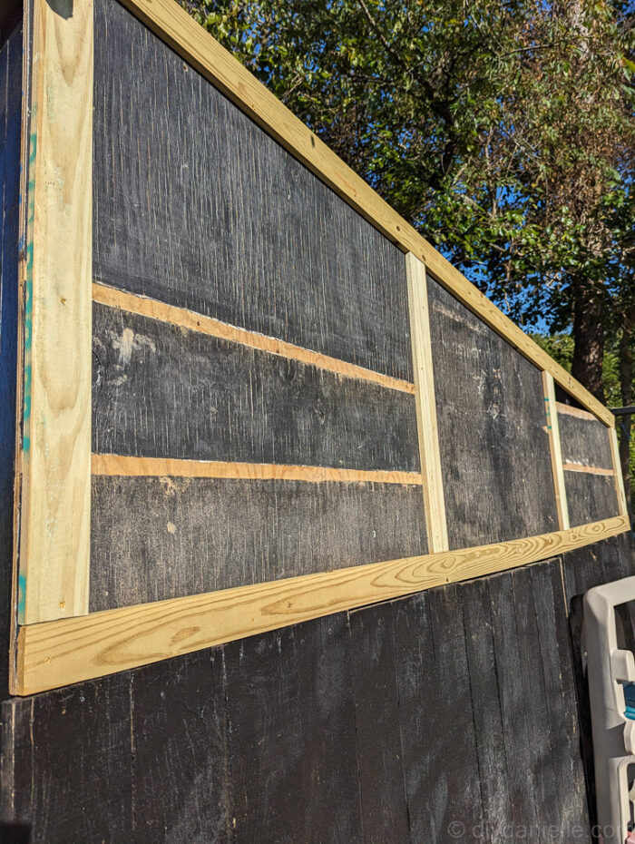 Close-up of upcycled wood siding and trim being installed on a DIY run-in shed.