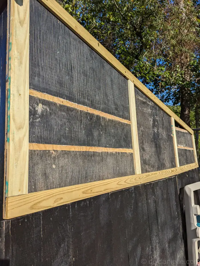 Close-up of upcycled wood siding and trim being installed on a DIY run-in shed.