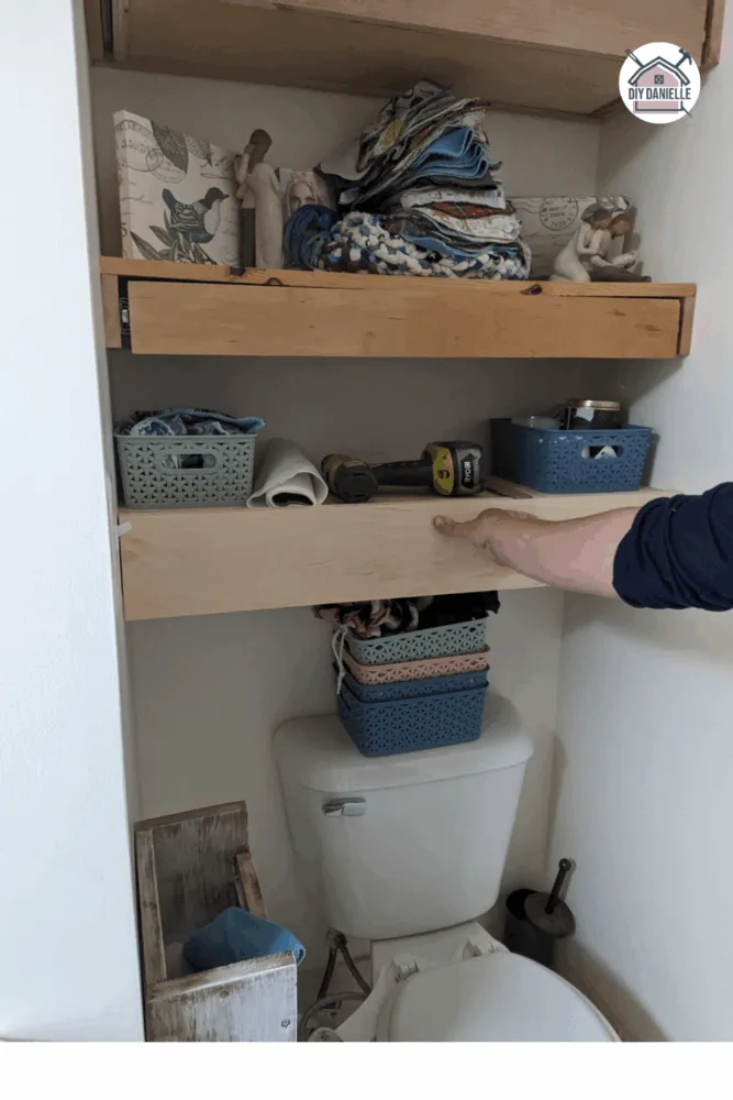 Wooden drawer front panel being held and aligned before gluing on a DIY drawer installation next to a light switch.