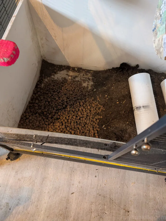 Clay pebbles used as a drainage layer in a small animal enclosure, with a suggestion to add a barrier to prevent mixing.