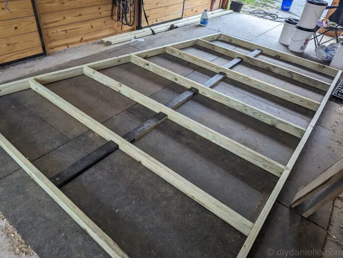 Back frame of a run-in shed with horizontal boards added between vertical supports for added stability.